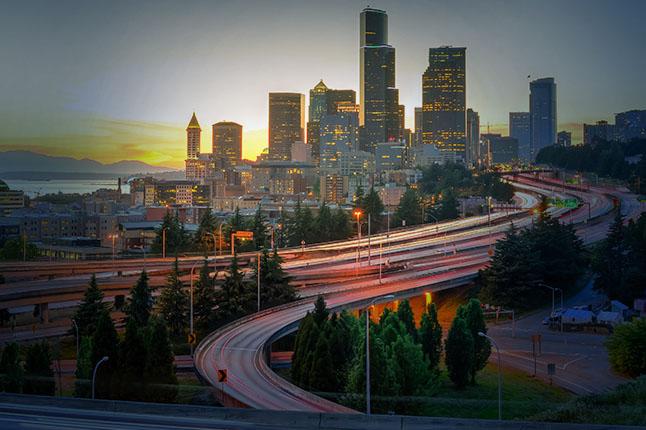 View of Seattle skyline at sunset, red taillights of traffic snaking through the city