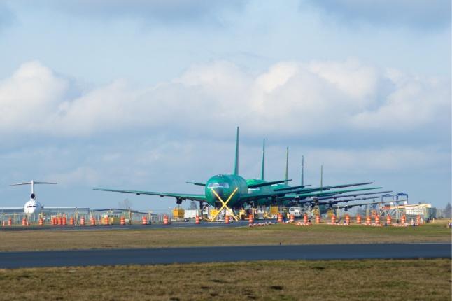 Newly-built planes on a runway, wrapped in green protective coating