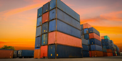 Stacked shipping containers against a sunset